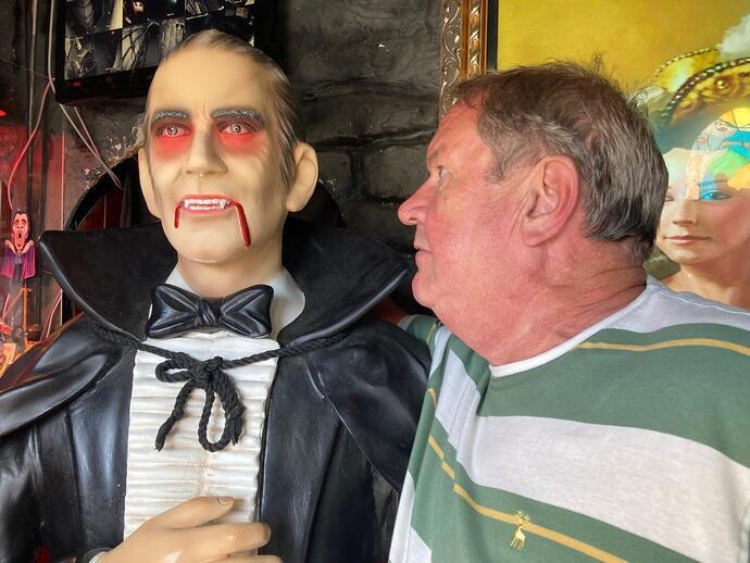 Homme observant attentivement une statue de cire représentant Dracula, dans le cadre de l'expérience Dracula