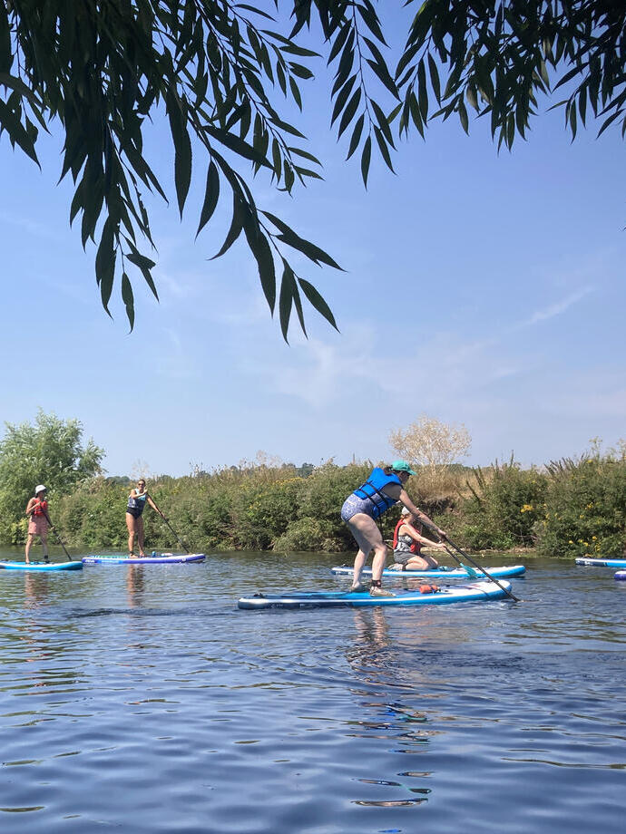 A group of people paddleboarding down the river Avon near Stratford-upon-Avon
