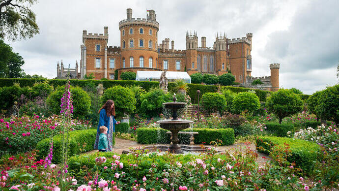 A woman and a child walk in the gardens of a castle