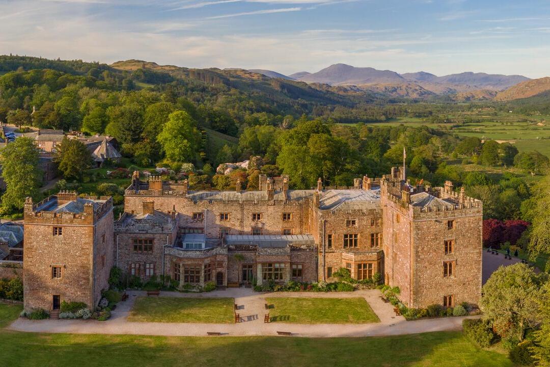 A country house with decorative mock foundations against a backdrop of tree covered hills