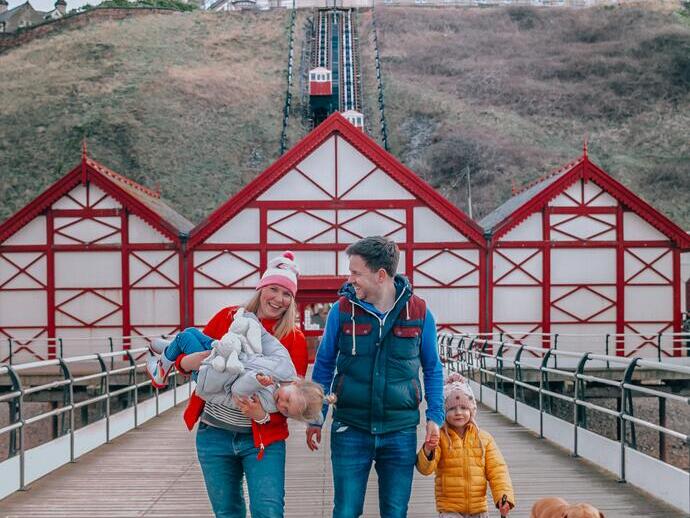 Family walking with a dog below a funicular cliff railway