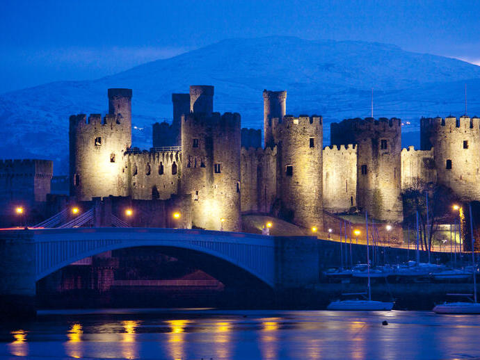 Un castillo iluminado por la noche junto al río