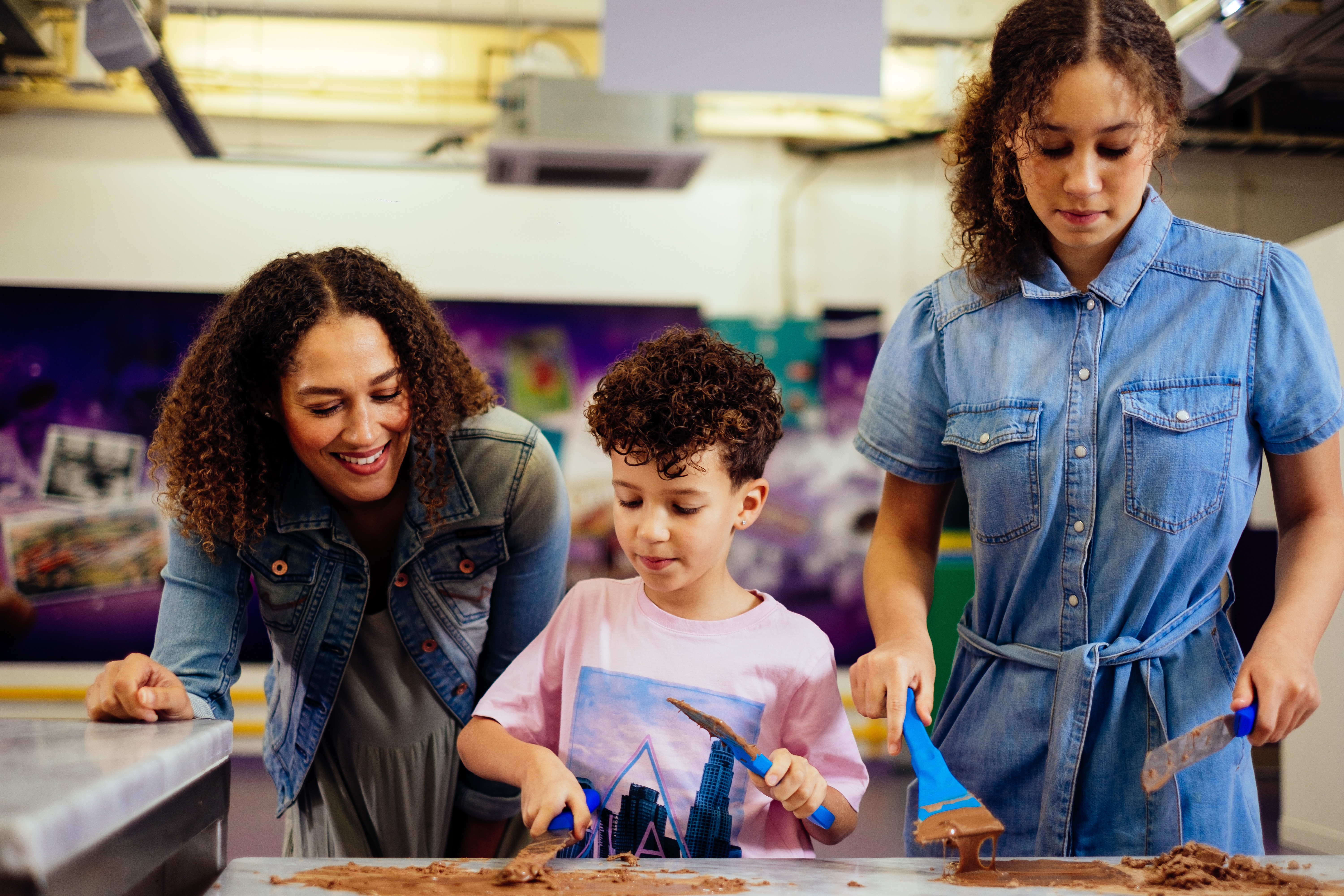 A boy, with curly hair, scraping chocolate off a table