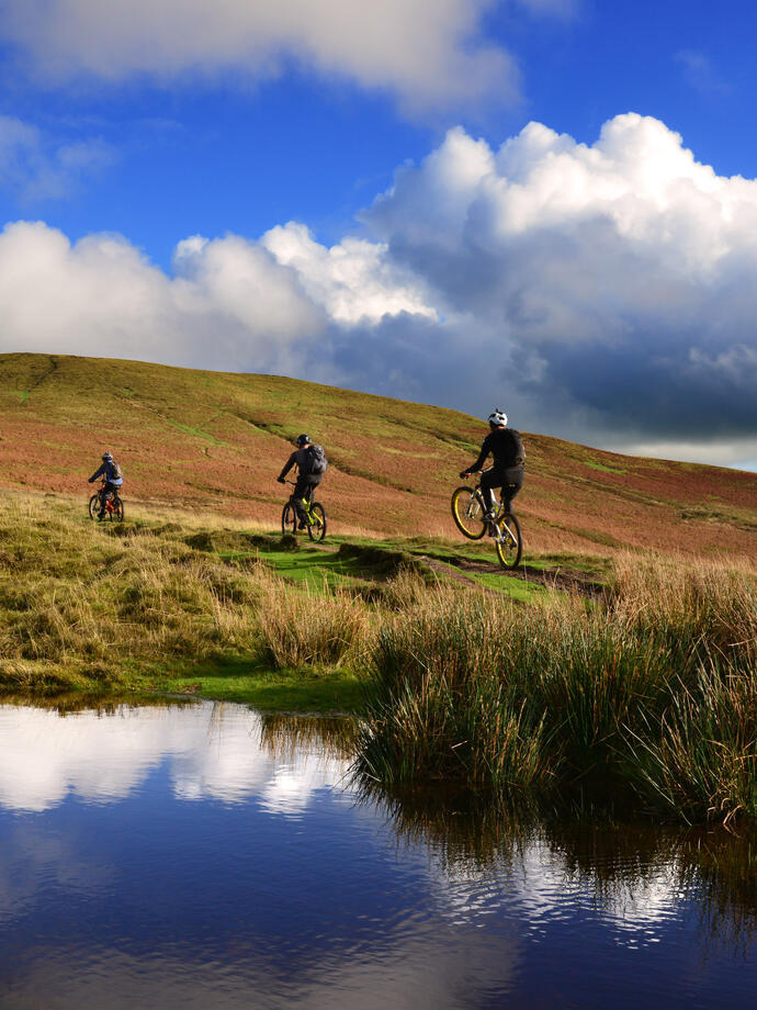 Mountain biking group traversing up a mountain range past a lake