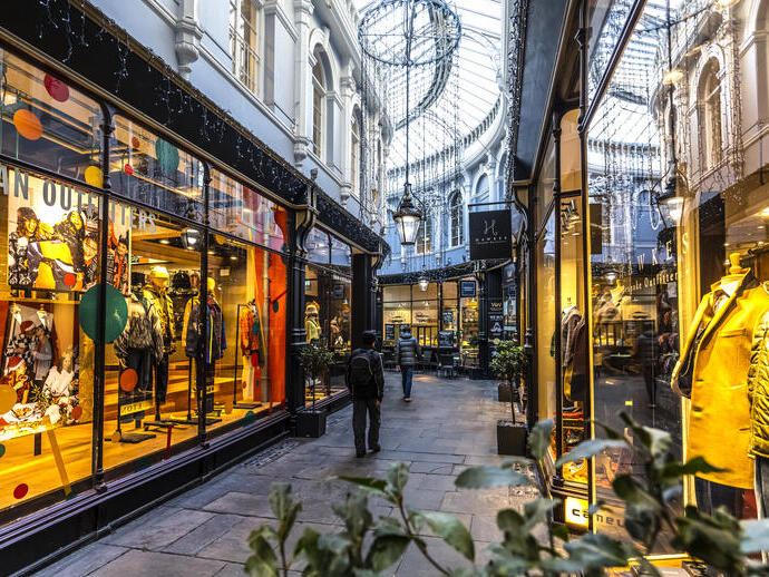 أشخاص يمشون بين المتاجر في ممر مضاء من الداخل