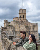 A man and a woman look out to a view from a castle