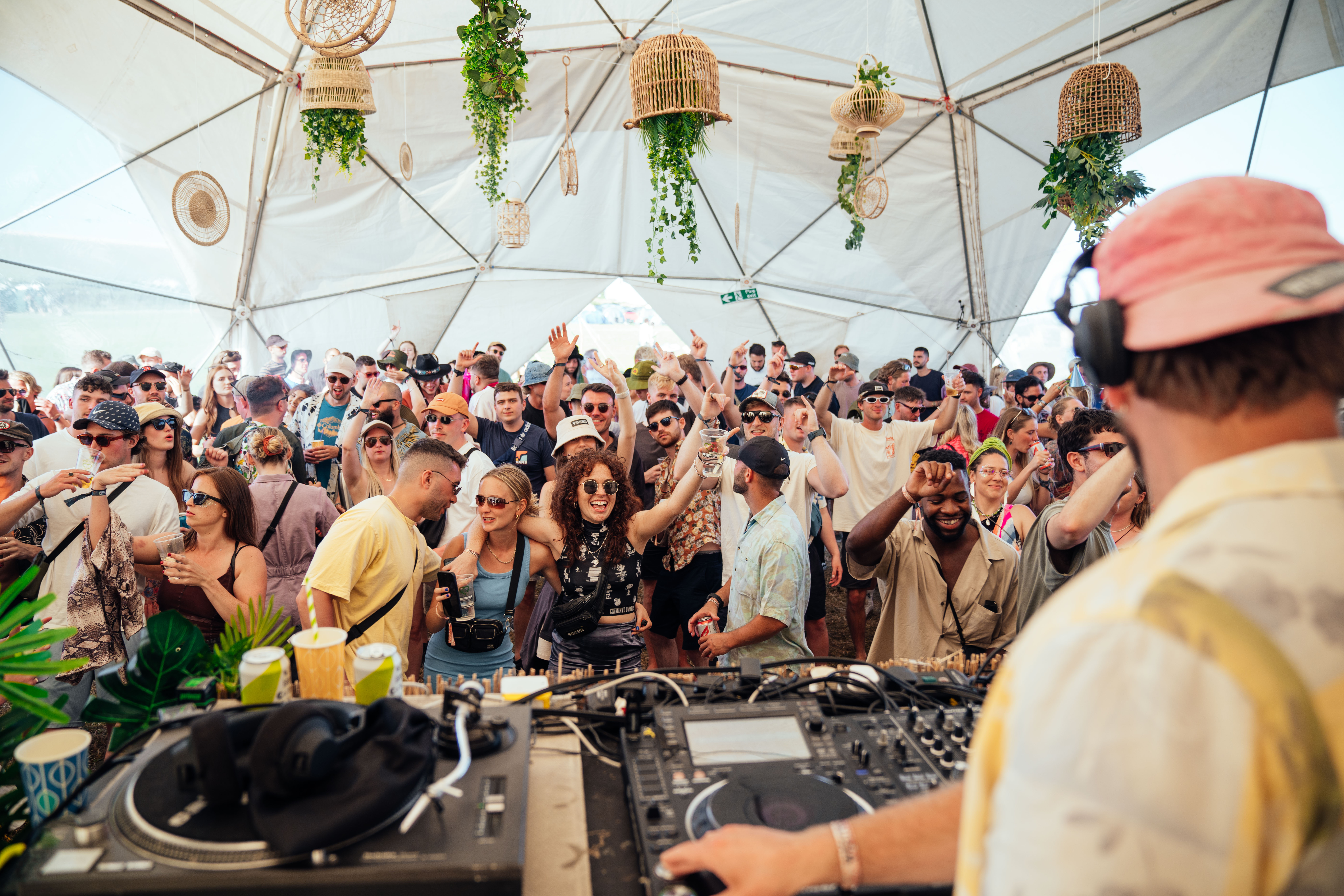 Une foule en délire devant un DJ lors d'un festival en plein air.