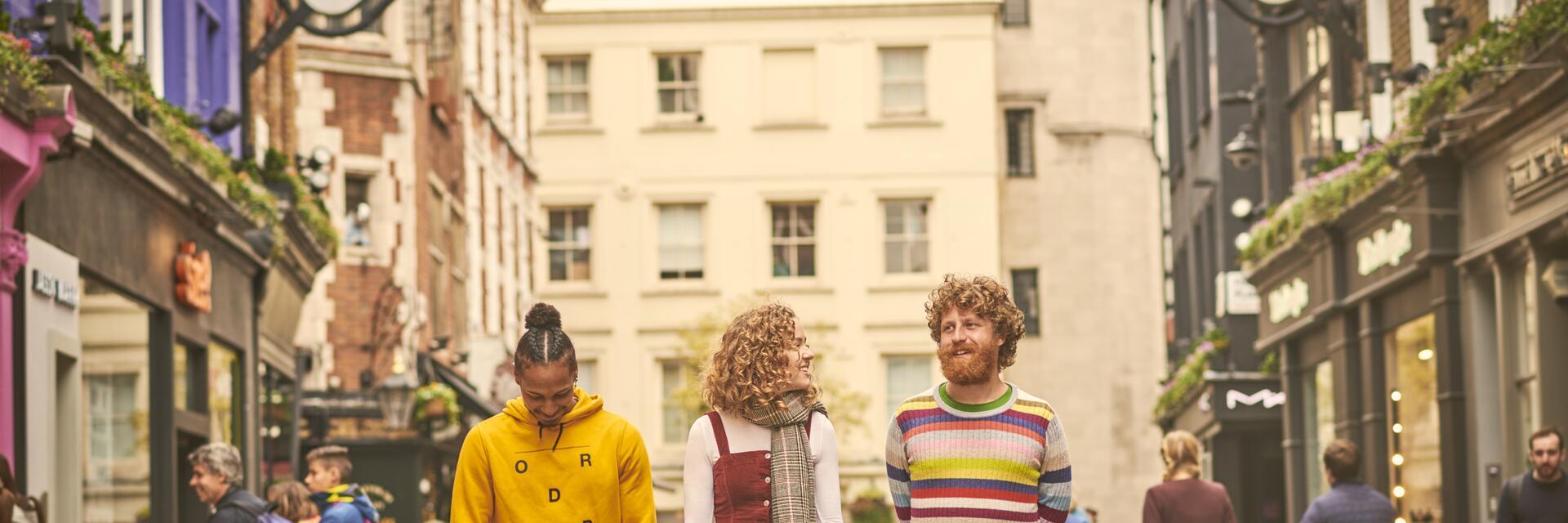 امرأة ورجلان يسيران في شارع للتسوق