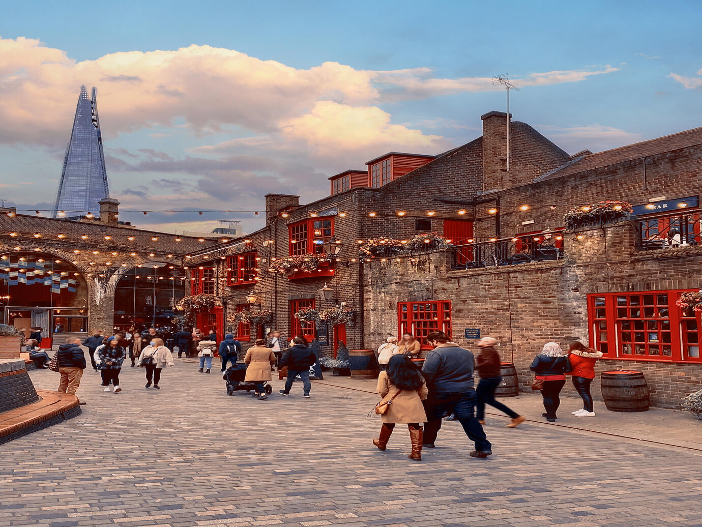 People walking past a pub, in Southwark with the Shard building in the distance
