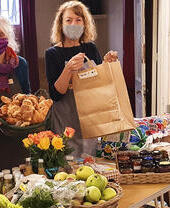 Frauen, die Speisen an einem Tisch im Planet Food, einem Gemeinschaftscafé und -laden in York, servieren