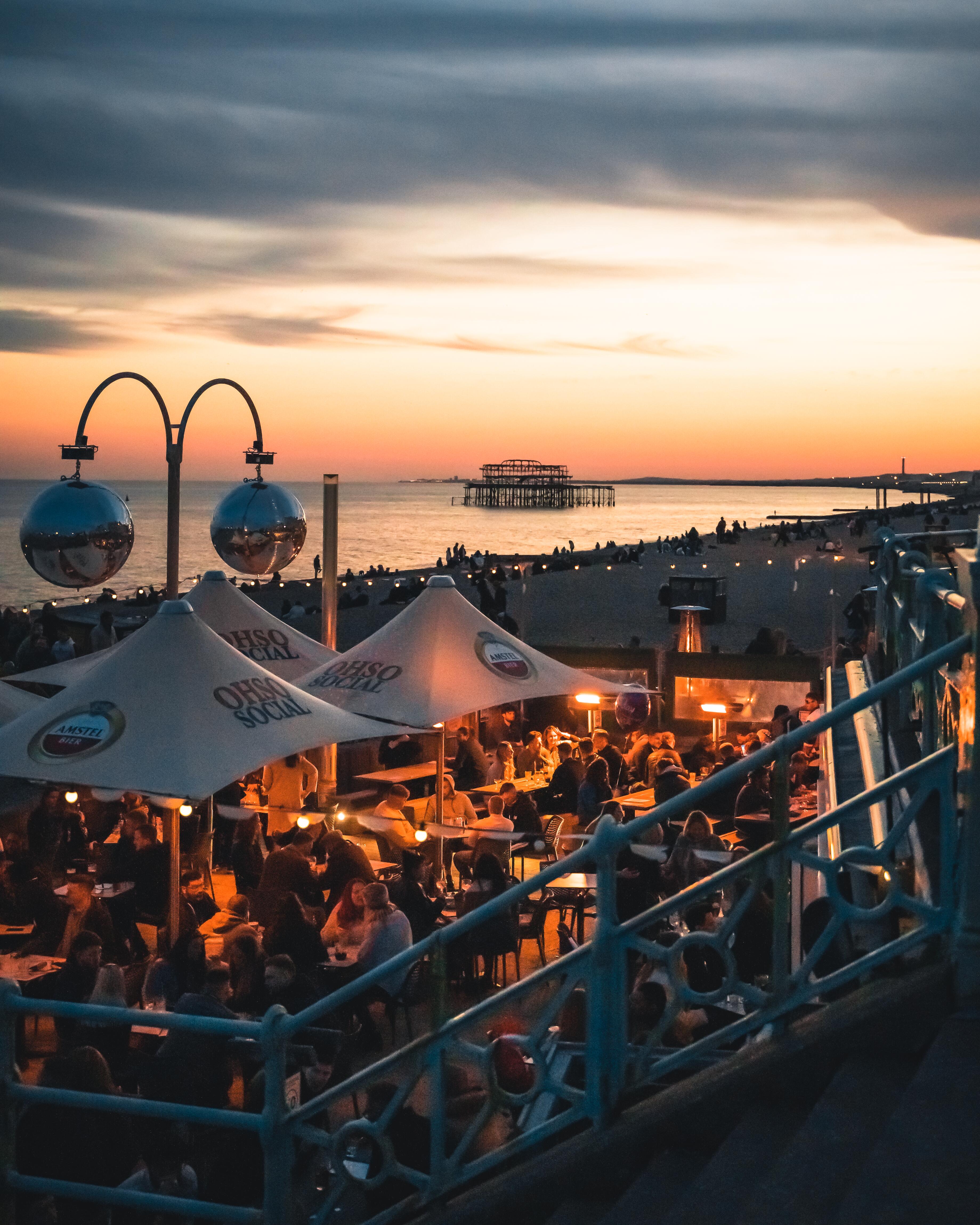 People enjoy drinks at a bar on the seafront at sundown