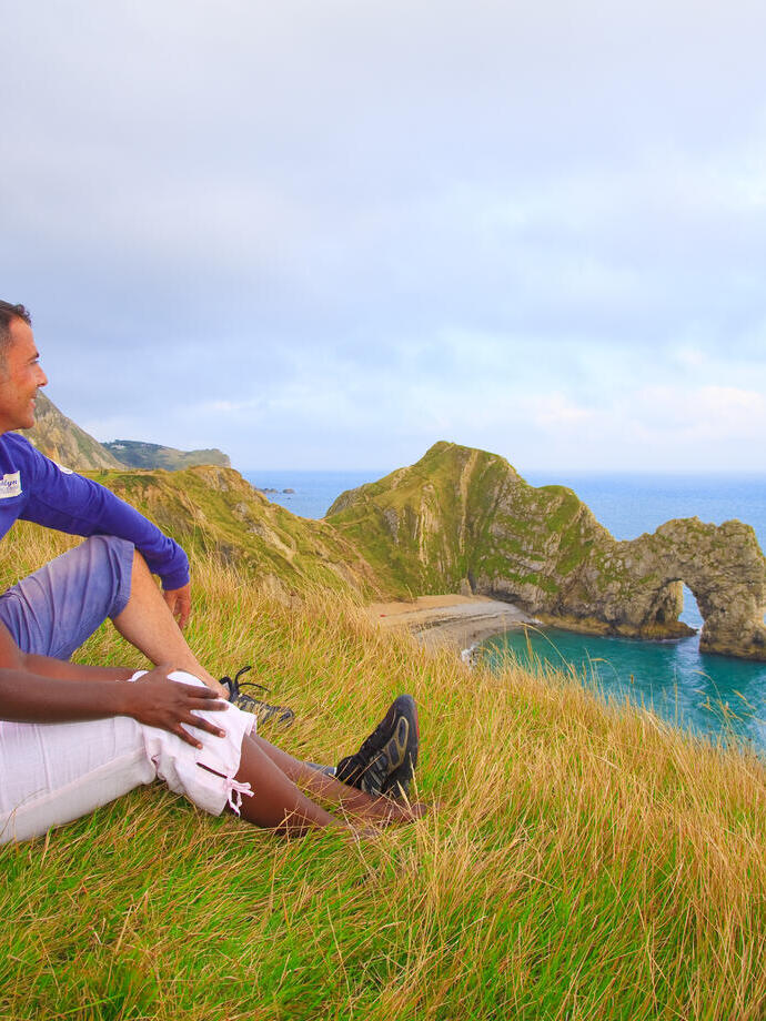 Couple sat on the grass looking out to the sea