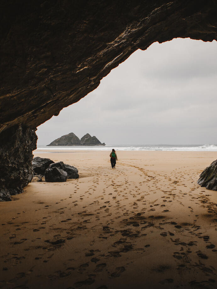Une femme marche dans une grotte sur une plage
