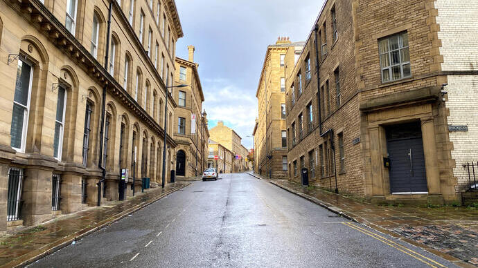 Looking up a deserted road, lined with Victorian stone buildings