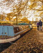 Two people walk alongside a canal in the autumn