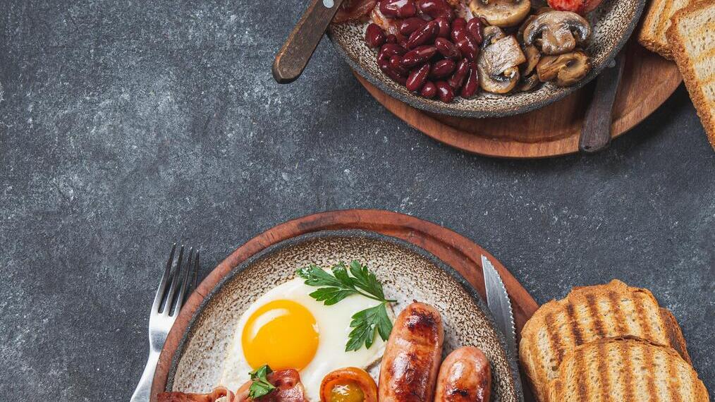 Zwei Teller mit einem kompletten englischen Frühstück auf einem Tisch