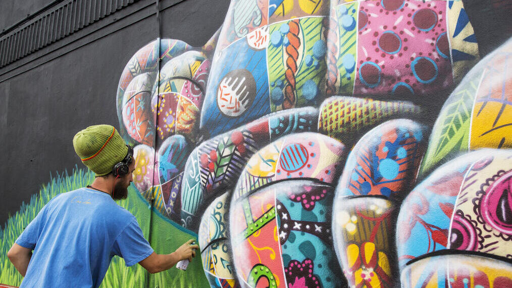 An artist using spray paint to design a piece of street artwork.