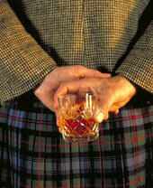 Scotsman with glass of whiskey held behind his back