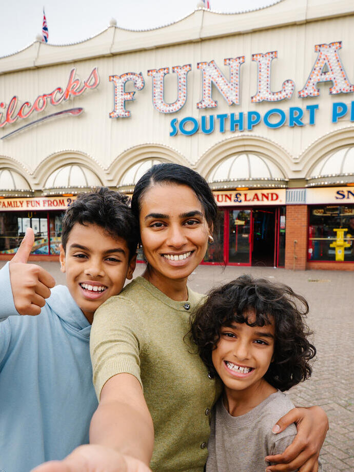 A mother and two sons stand outside an amusement park