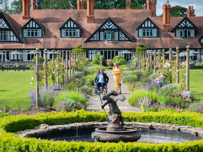 A woman and a man in a wheelchair smiling together in summer gardens