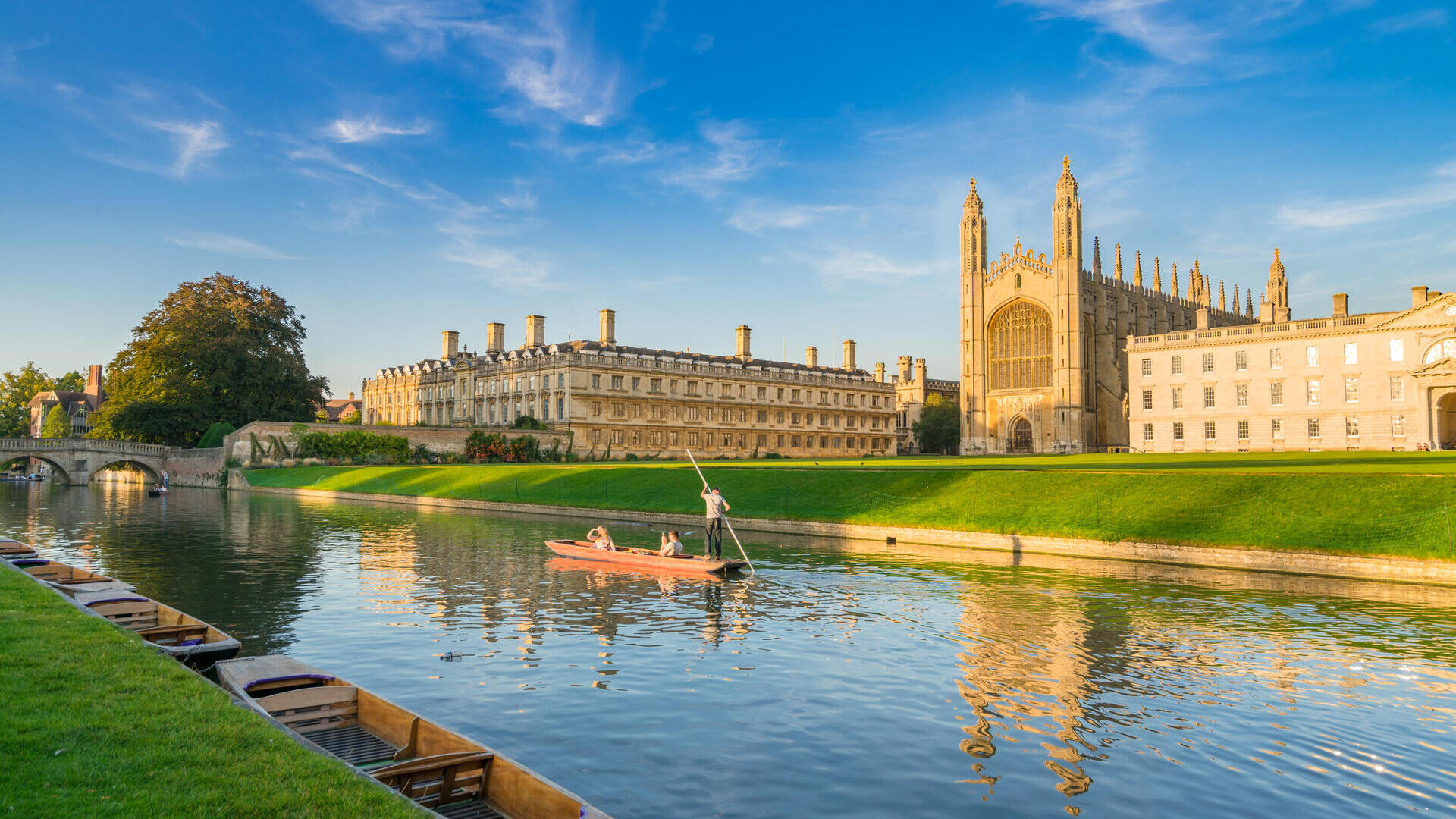 People punting along a river next to a college and chapel.