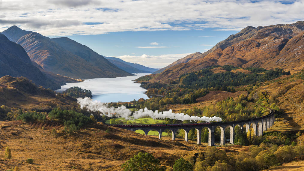 Blick auf das Tal in den Highlands und das Glenfinnan-Viadukt, Dampfzug auf den Gleisen, Loch Shiel im Hintergrund