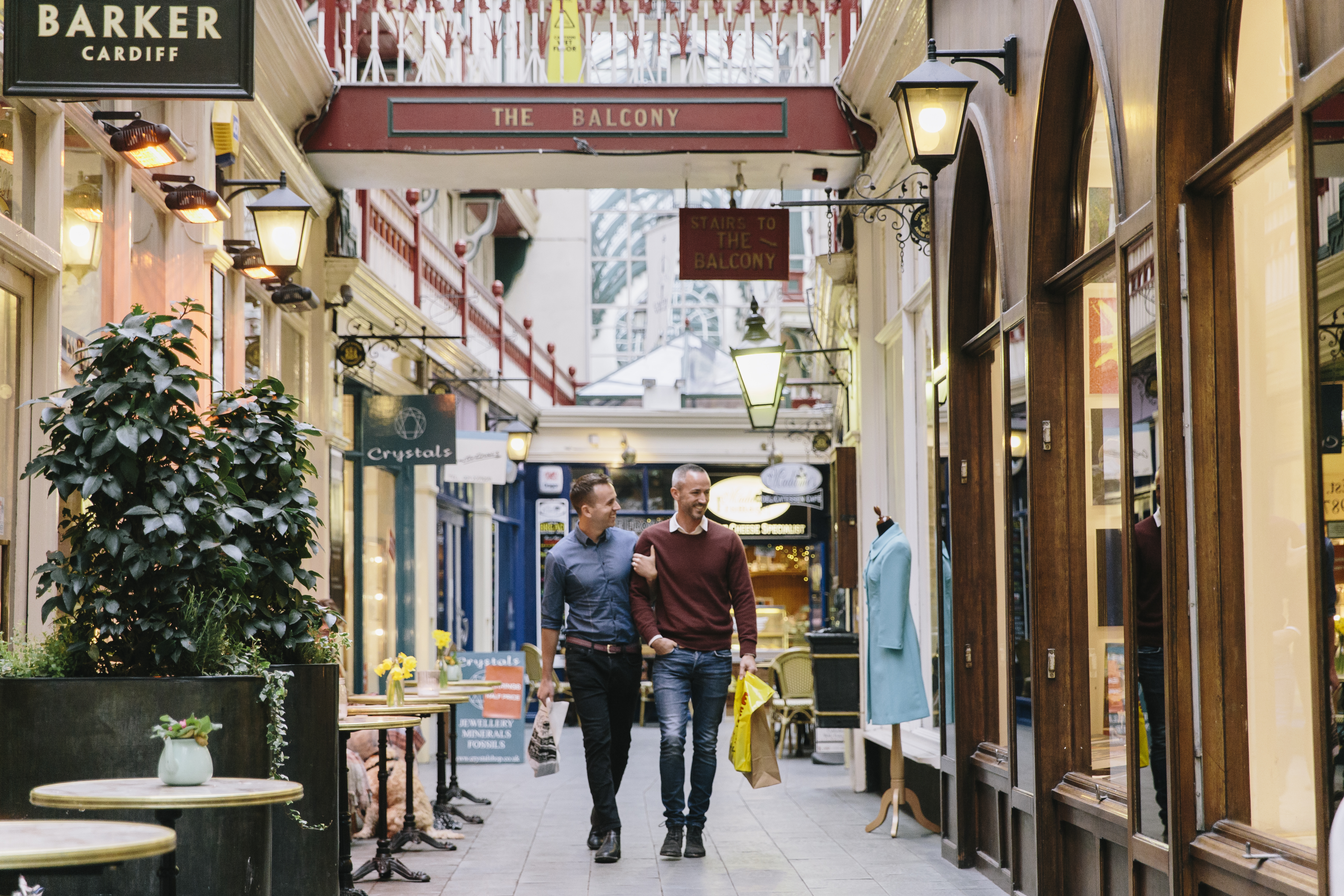 A gay couple, with arms linked, shopping indoors