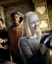 A woman touching an exhibit with two men in the background at Escape Hunt