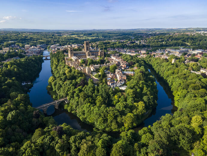 An elevated view of a Cathedral set amongst trees and a river