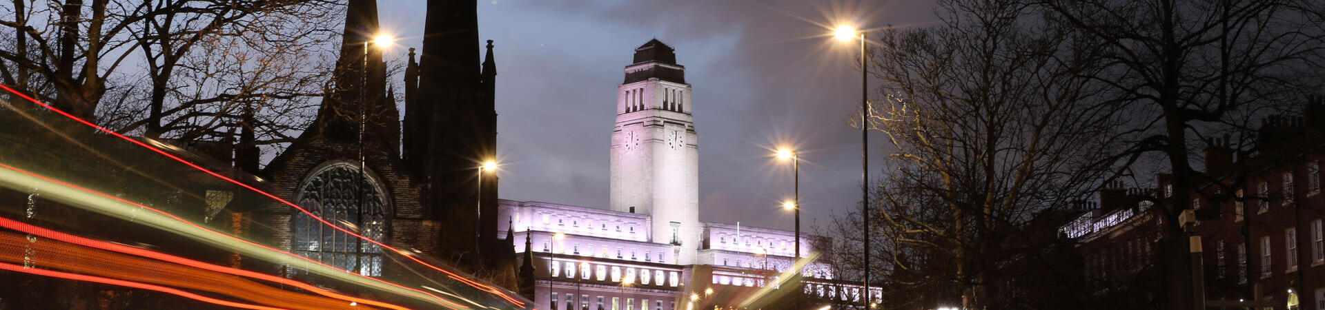 A view of a university taken from the street at night.