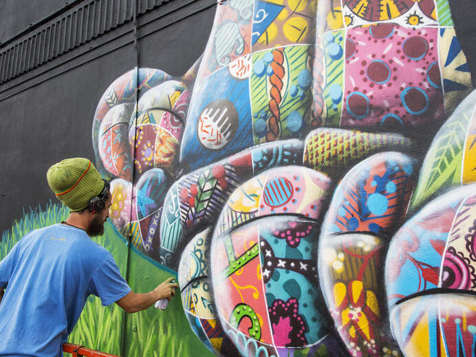 An artist using spray paint to design a piece of street artwork.