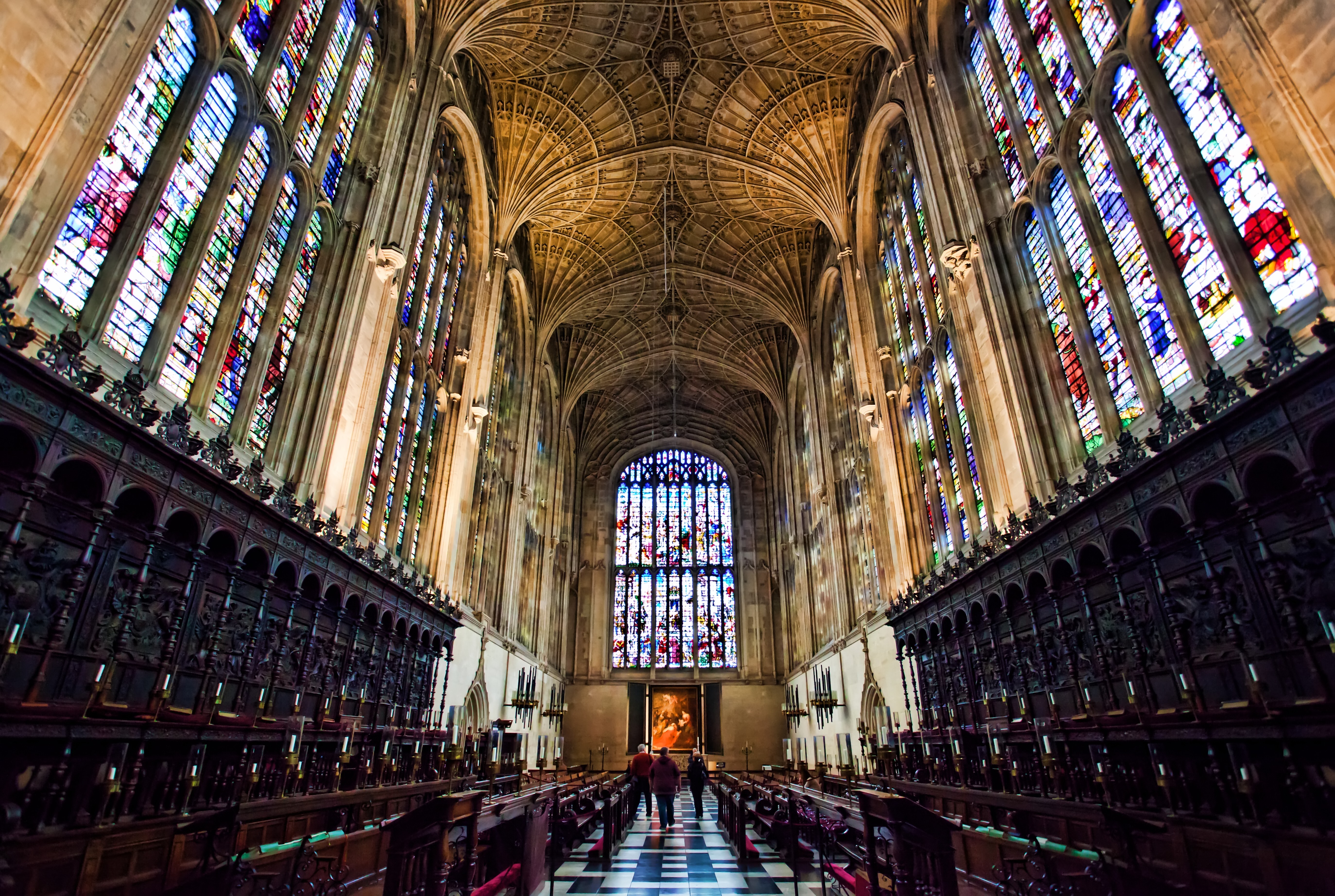 Inside Kings College Chapel, Cambridge, showing the fan vault ceiling and vast wooden panelling, with stain glass windows set above.