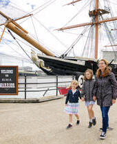 A family walking alongside a ship at a dock
