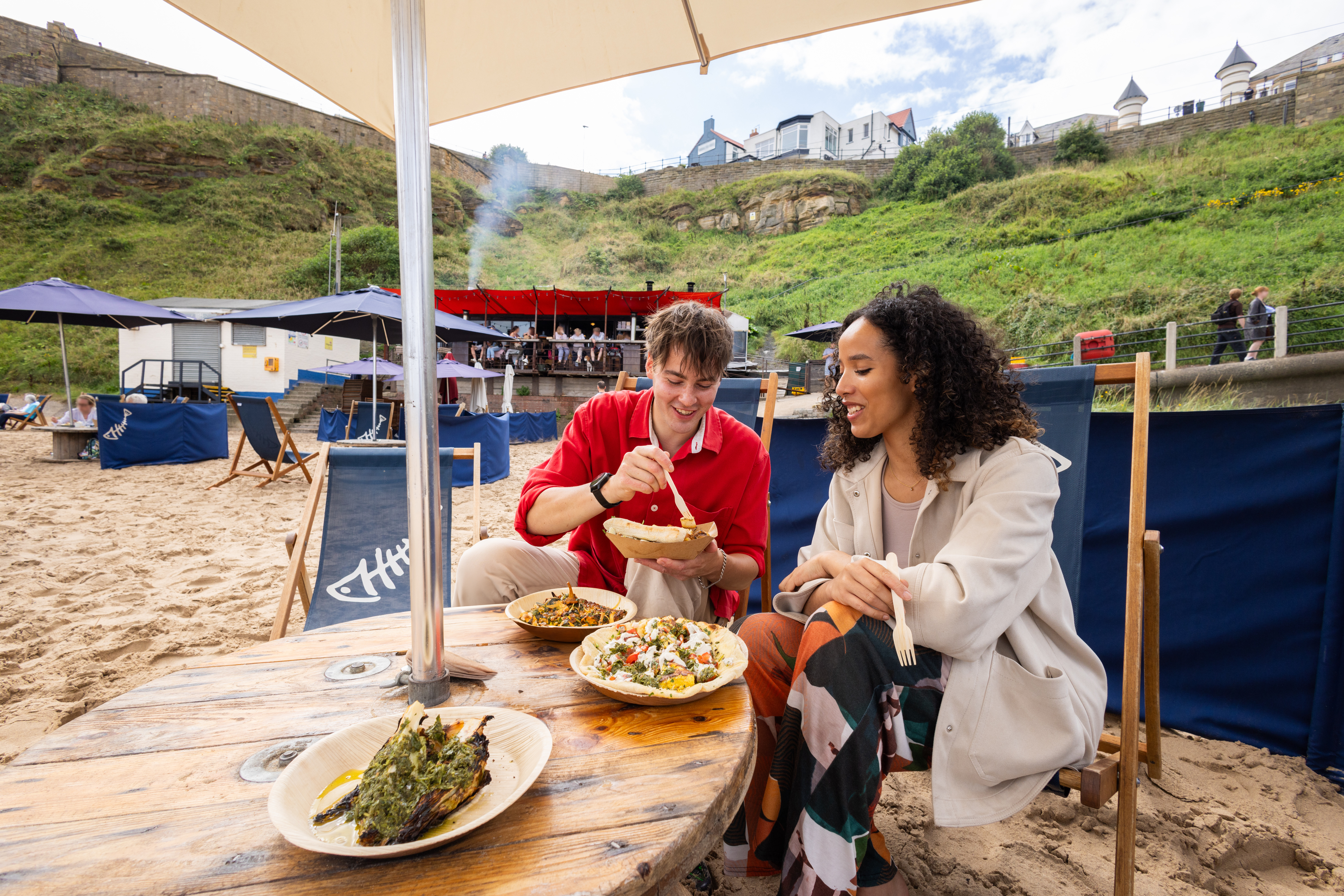 Couple eating food at a beach café and restaurant with the sea in the background