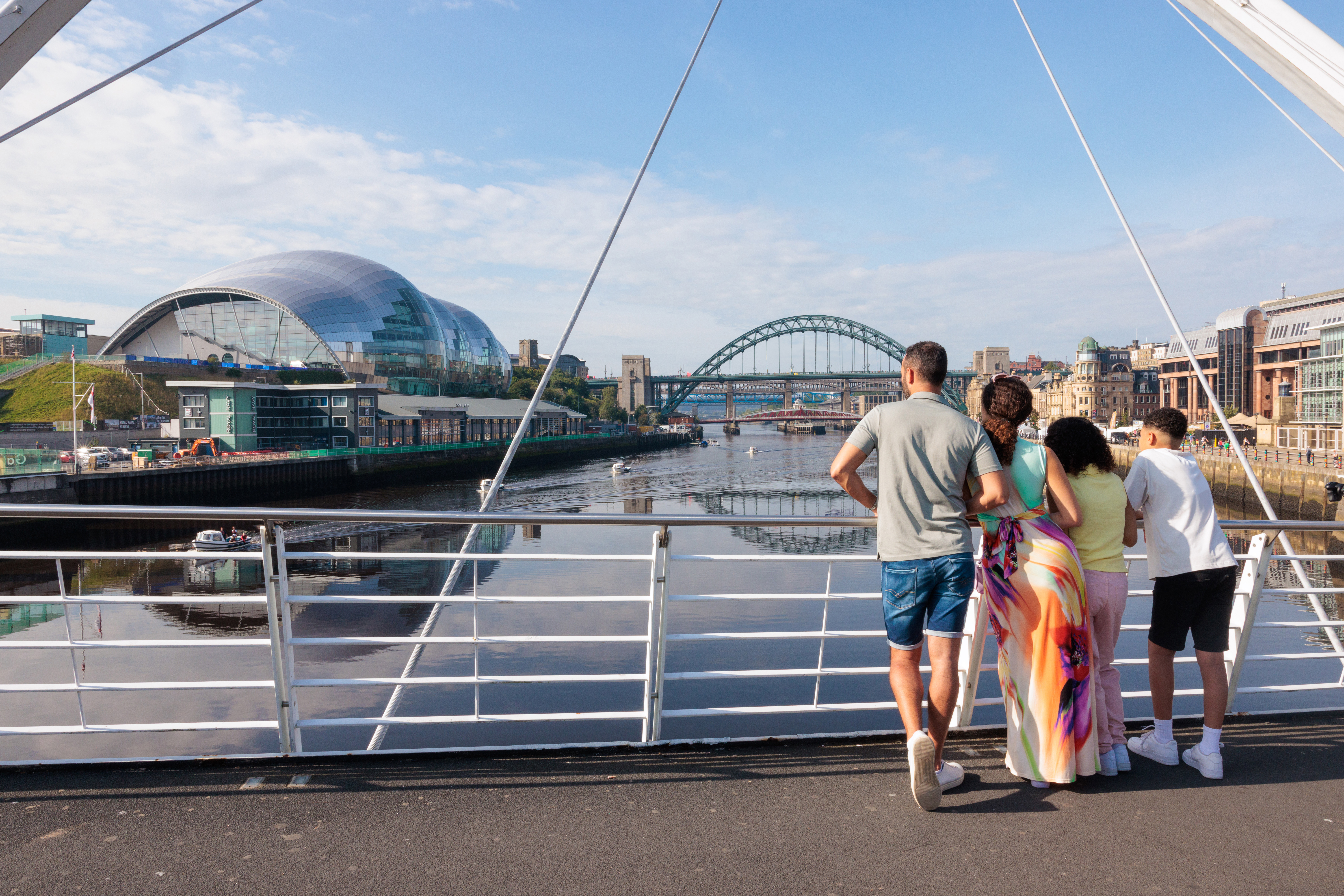 Family standing on a bridge overlooking a city river