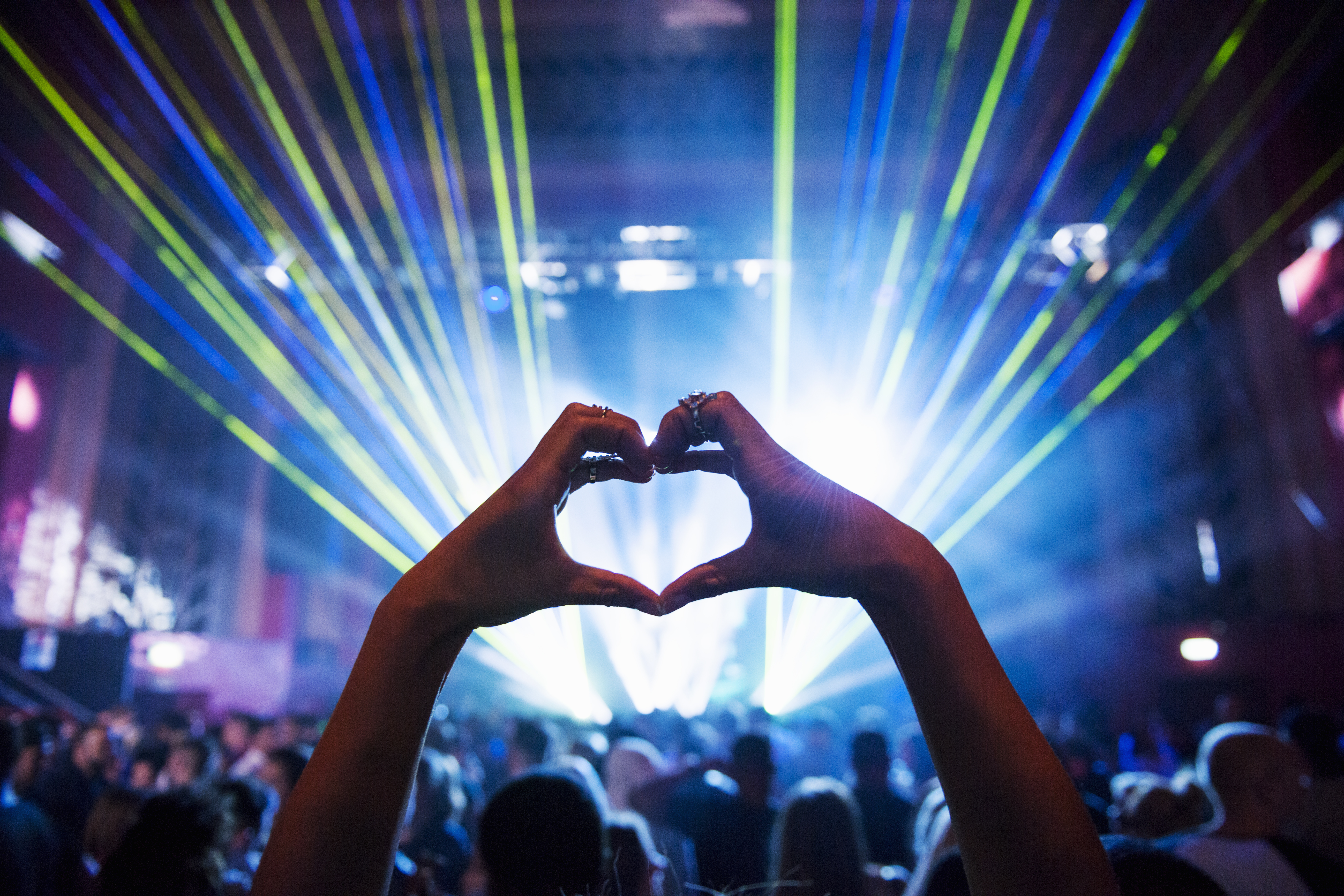 Woman making heart shape with hands at a music event