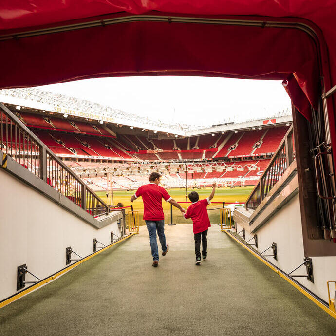 Un hombre y un niño en el túnel del estadio mirando hacia el campo