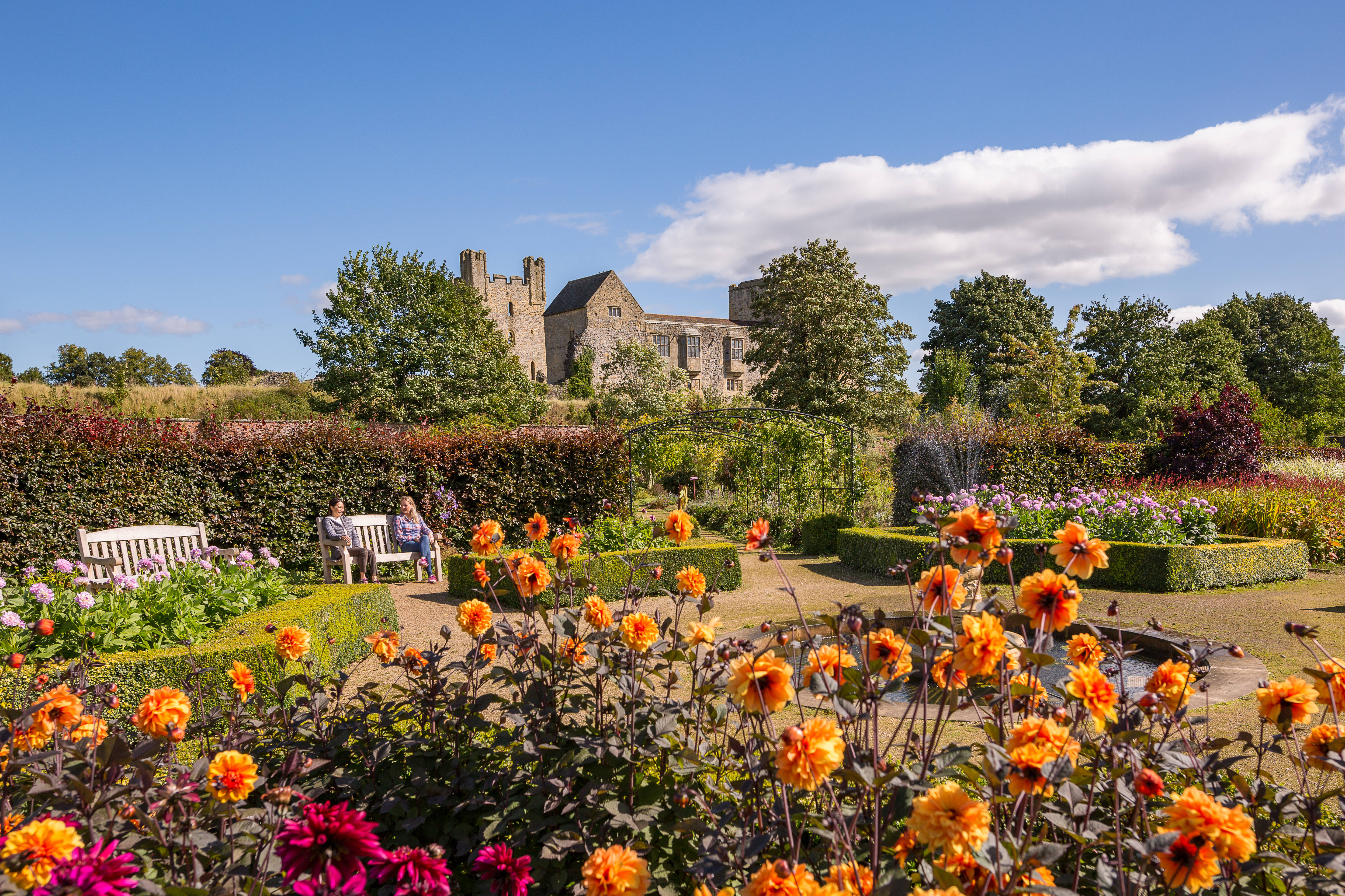 Two female friends walking through a formal garden