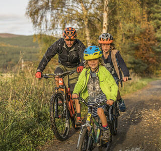 Adult and two children cycling on a path through the countryside