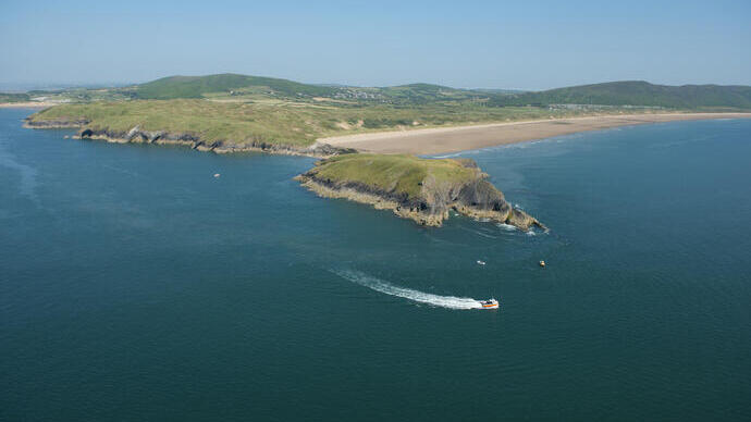 Un motoscafo in mare segue la costa in acque blu intenso