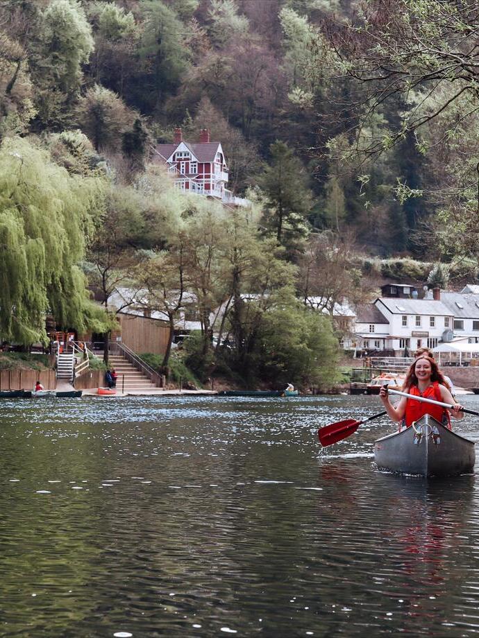 A woman in a canoe with hills and buildings behind