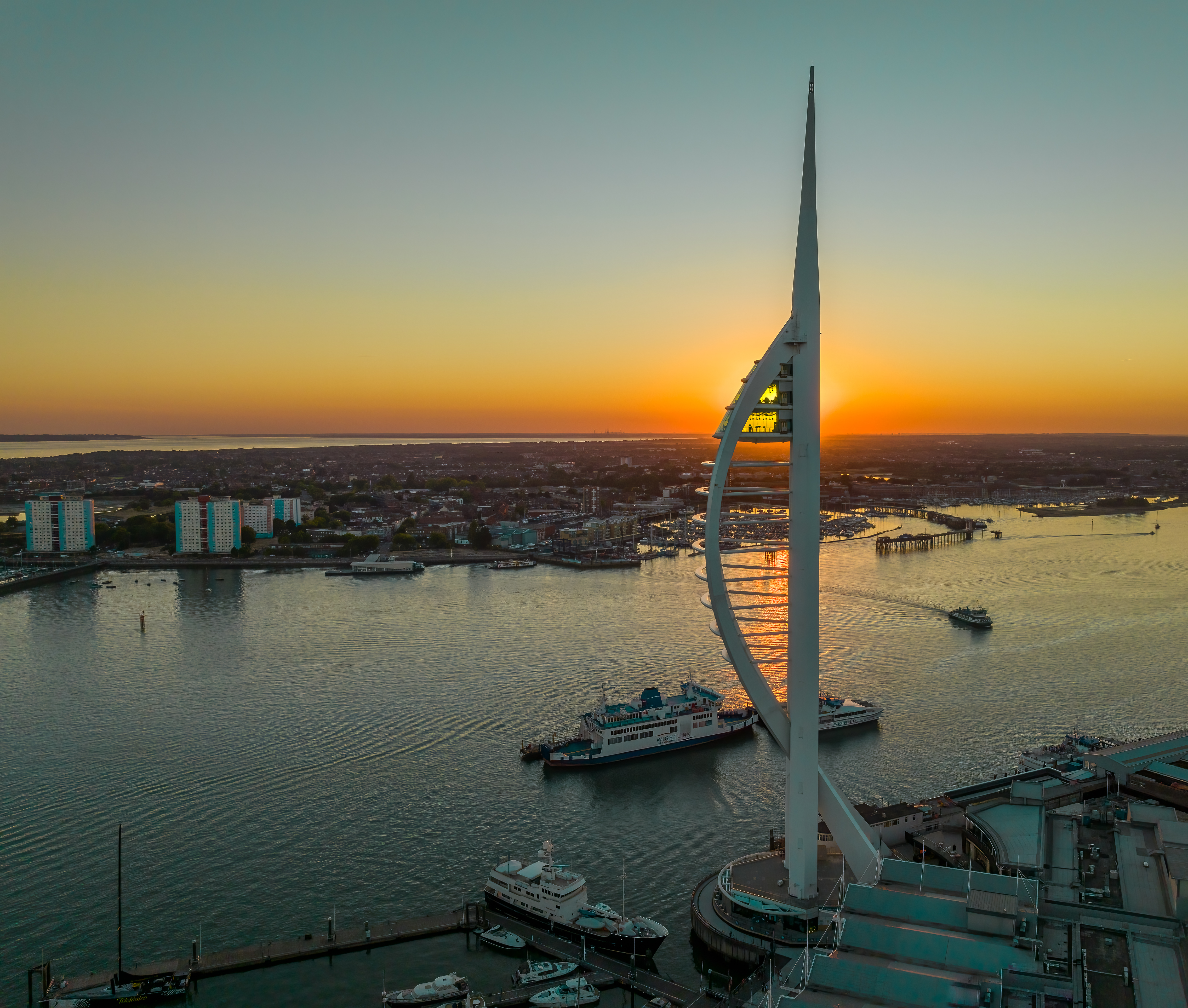 A modern tower next to the ocean at sunset
