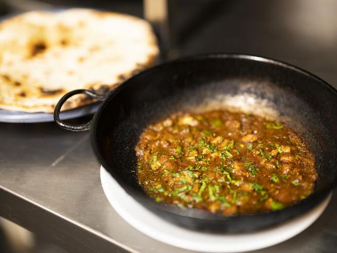Una padella di ferro piena di curry e pane naan