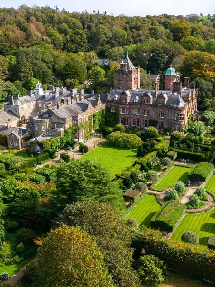Aerial view of country house surrounded by rolling hills and green trees