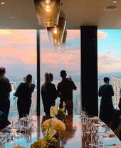 A group of people drinking while looking out over Manchester's skyline in a private room at 20 Stories Restaurant