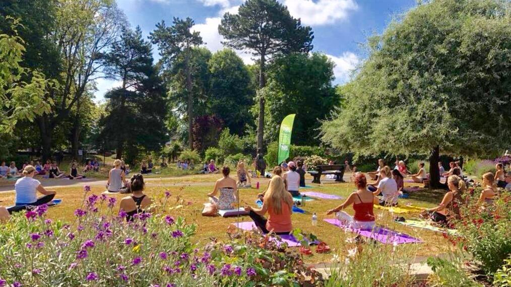 Grupos de personas haciendo una sesión de yoga en un parque de la Costa Jurásica