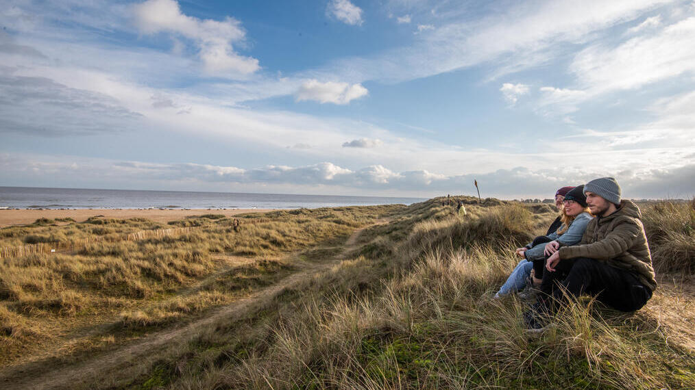A group of people looking out at the sea from Winterton Dunes