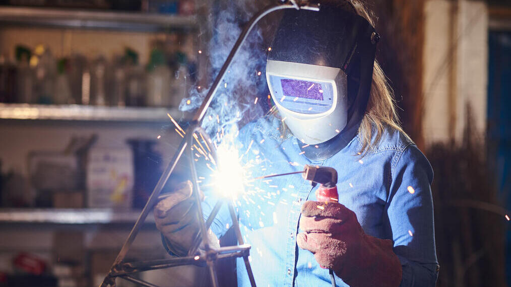 Woman working on soldering sculpture in workshop