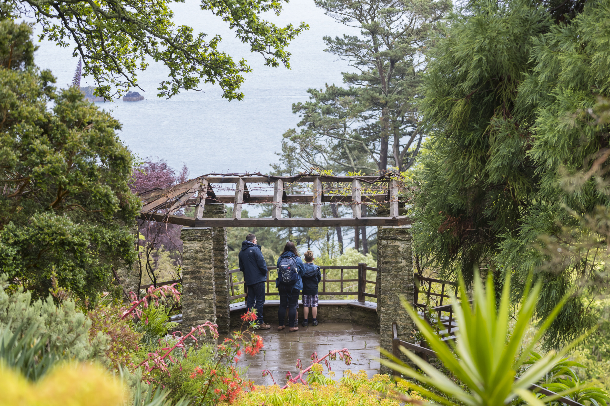 Visitors taking in the view of the sea from the garden at Coleton Fishacre