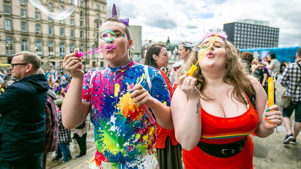 Deux personnes célébrant la Liverpool Pride en soufflant des bulles vers l'appareil photo